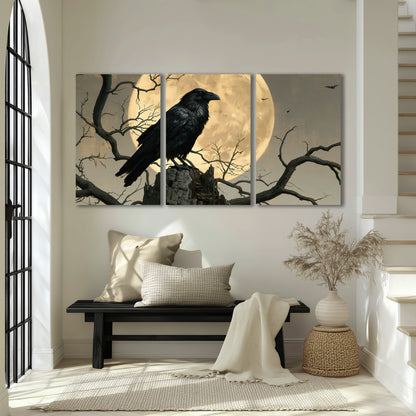 A black raven standing among bare branches in front of a large golden moon 3 piece canvas wall art displayed in a entryway