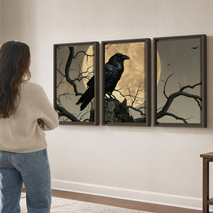A black raven standing among bare branches in front of a large golden moon 3 piece framed canvas wall art three panel arrangement on a wall