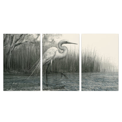 A pale long-legged heron standing beside tall reeds in a muted gray-green wetland 3 piece canvas wall art viewed straight on