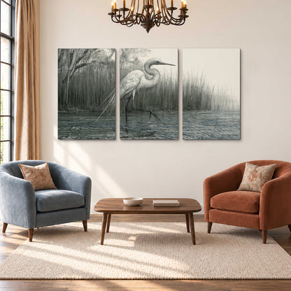 A pale long-legged heron standing beside tall reeds in a muted gray-green wetland 3 piece canvas wall art styled in an interior