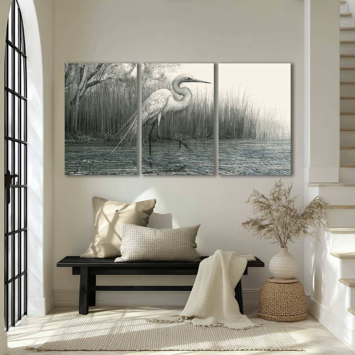 A pale long-legged heron standing beside tall reeds in a muted gray-green wetland 3 piece canvas wall art displayed in a entryway
