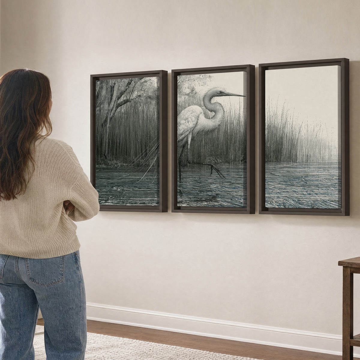 A pale long-legged heron standing beside tall reeds in a muted gray-green wetland 3 piece framed canvas wall art three panel arrangement on a wall