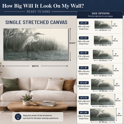 A pale long-legged heron standing beside tall reeds in a muted gray-green wetland single canvas wall art size guide above a sofa; room view is illustrative