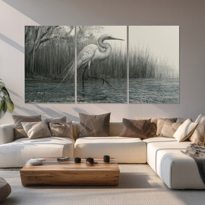 A pale long-legged heron standing beside tall reeds in a muted gray-green wetland set of 3 poster prints displayed in a living room