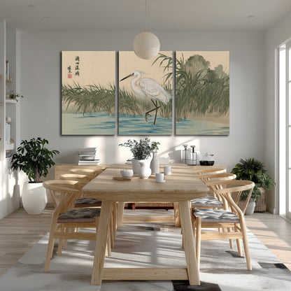 A white heron standing beside a quiet river with reeds and distant hills 3 piece canvas wall art room and product view