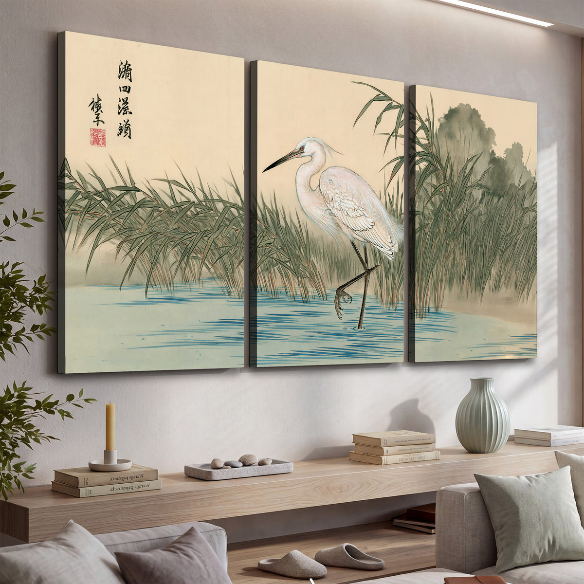A white heron standing beside a quiet river with reeds and distant hills 3 piece canvas wall art displayed in a console