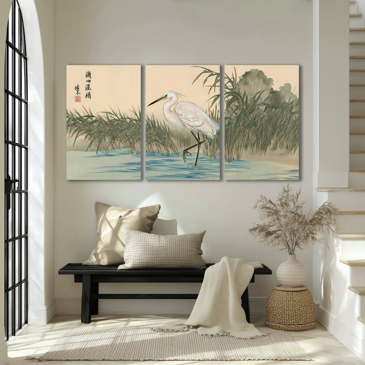 A white heron standing beside a quiet river with reeds and distant hills 3 piece canvas wall art displayed in a entryway