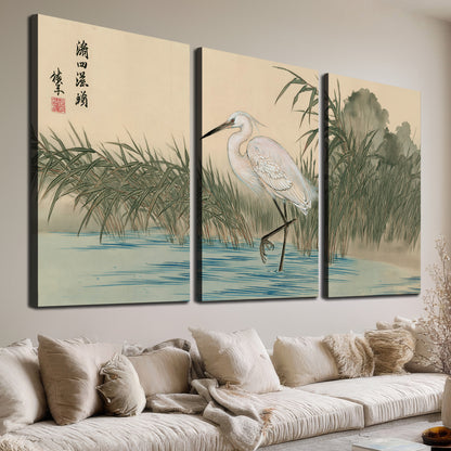 A white heron standing beside a quiet river with reeds and distant hills 3 piece canvas wall art room and product view