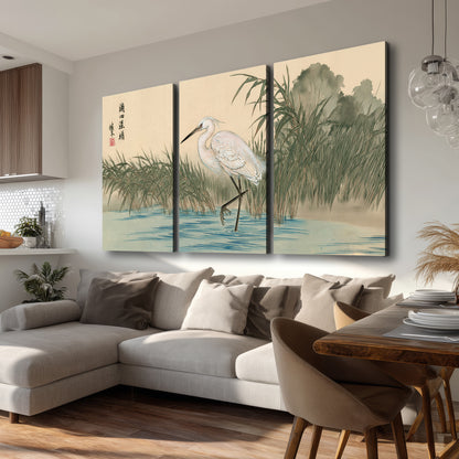 A white heron standing beside a quiet river with reeds and distant hills 3 piece canvas wall art room and product view