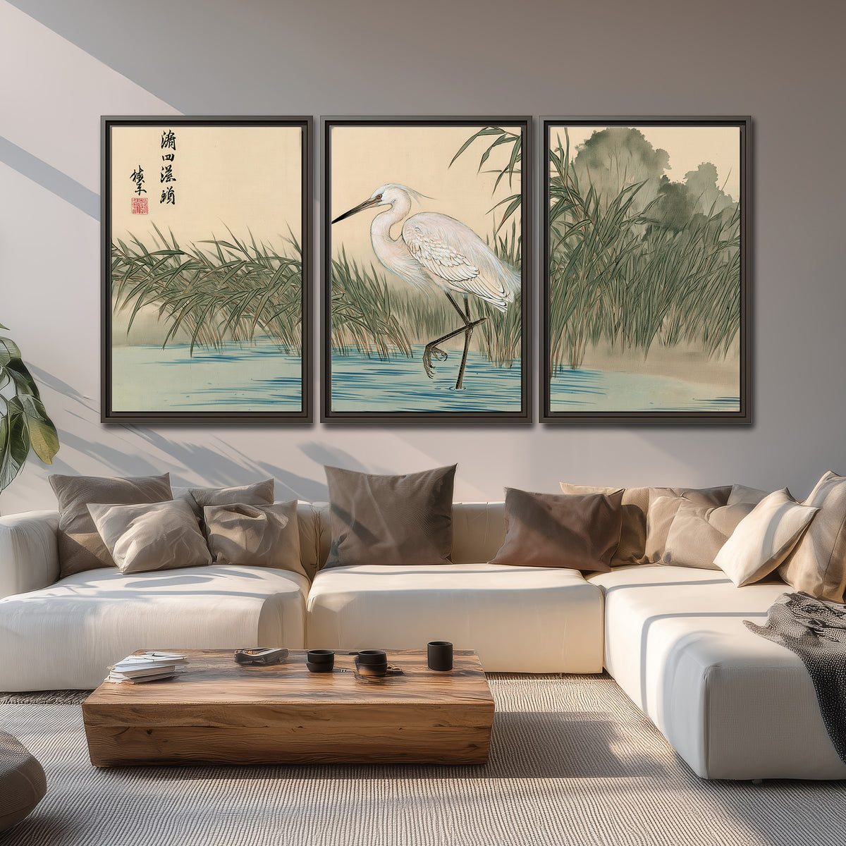 A white heron standing beside a quiet river with reeds and distant hills 3 piece framed canvas wall art displayed in a living room