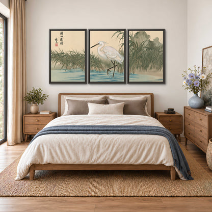 A white heron standing beside a quiet river with reeds and distant hills 3 piece framed canvas wall art styled in an interior