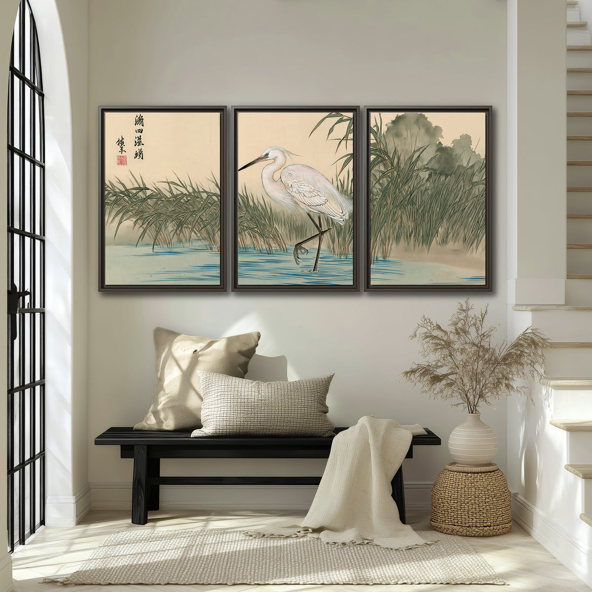 A white heron standing beside a quiet river with reeds and distant hills 3 piece framed canvas wall art displayed in a entryway