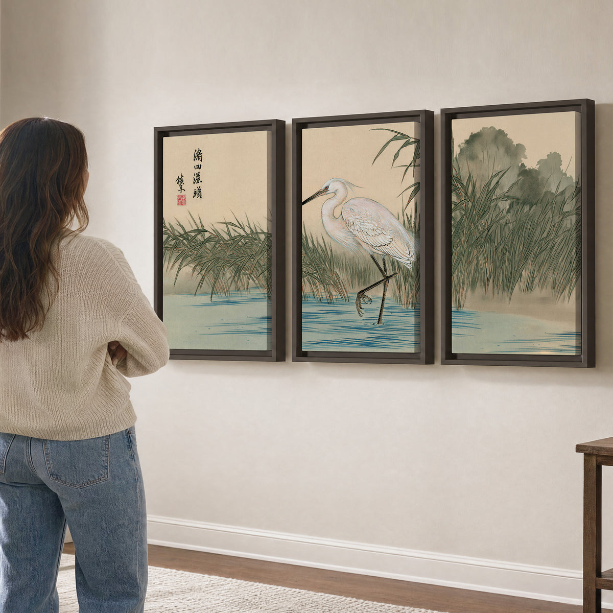 A white heron standing beside a quiet river with reeds and distant hills 3 piece framed canvas wall art three panel arrangement on a wall