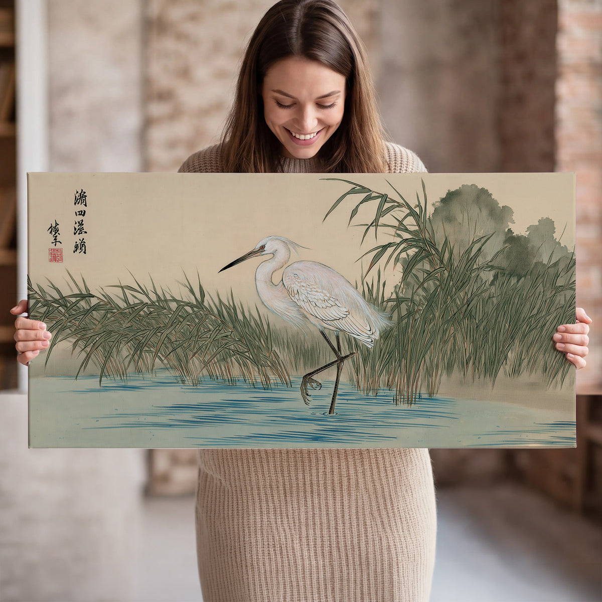 A white heron standing beside a quiet river with reeds and distant hills single canvas wall art held in hands