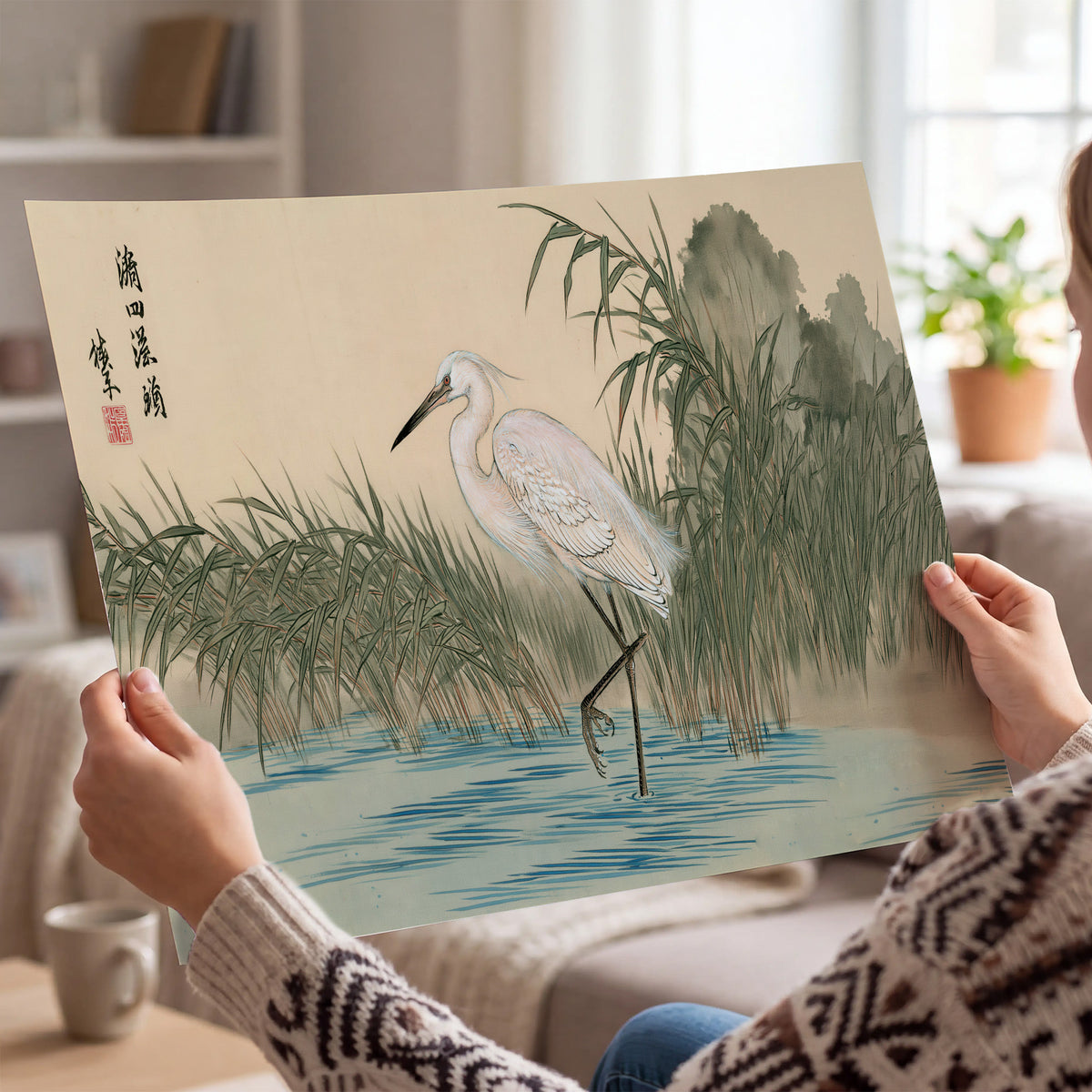 A white heron standing beside a quiet river with reeds and distant hills single poster print held in hands