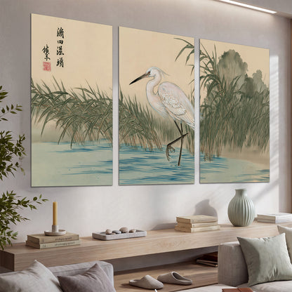 A white heron standing beside a quiet river with reeds and distant hills set of 3 poster prints displayed in a console