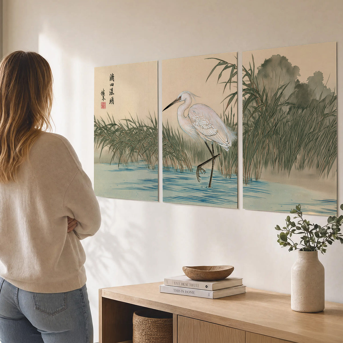 A white heron standing beside a quiet river with reeds and distant hills set of 3 poster prints three panel arrangement on a wall