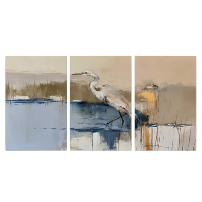 A slender heron standing in blue water among loose ochre and cream brushstrokes 3 piece canvas wall art viewed straight on