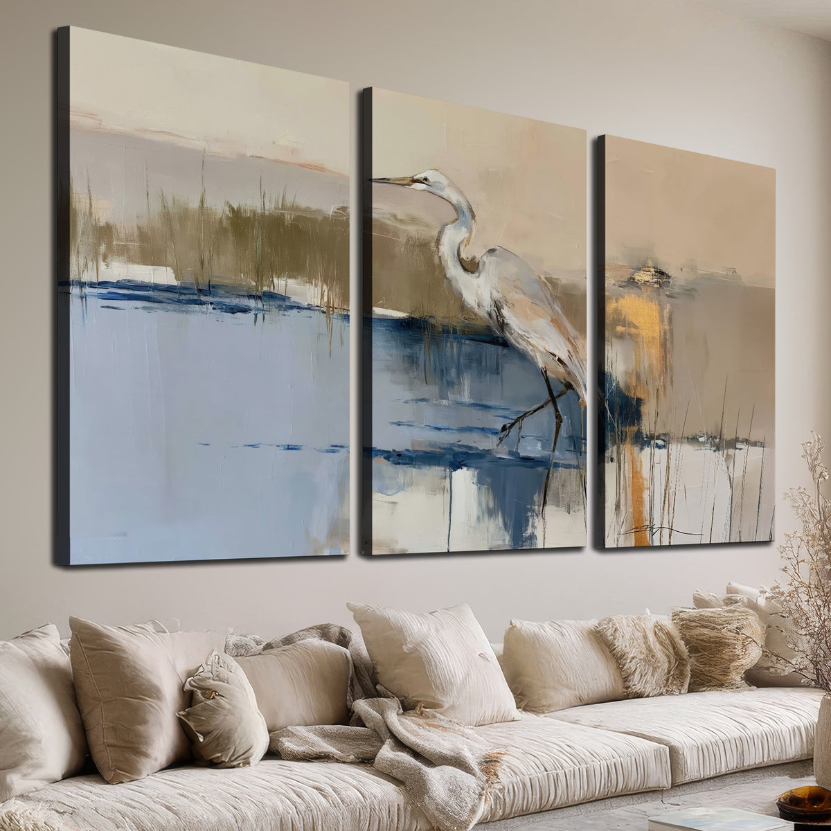A slender heron standing in blue water among loose ochre and cream brushstrokes 3 piece canvas wall art room and product view