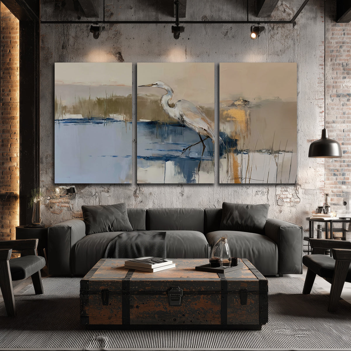 A slender heron standing in blue water among loose ochre and cream brushstrokes 3 piece canvas wall art displayed in a industrial room