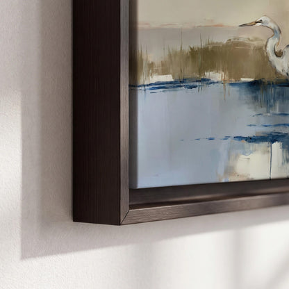 A slender heron standing in blue water among loose ochre and cream brushstrokes 3 piece framed canvas wall art material and edge close up