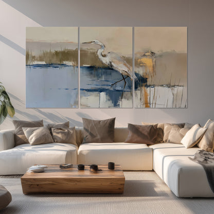 A slender heron standing in blue water among loose ochre and cream brushstrokes set of 3 poster prints displayed in a living room
