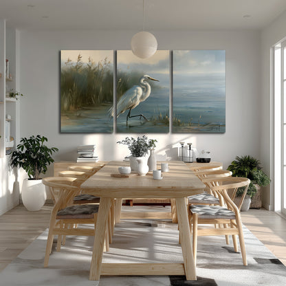 A white heron beside tall marsh grasses and still blue water 3 piece canvas wall art room and product view