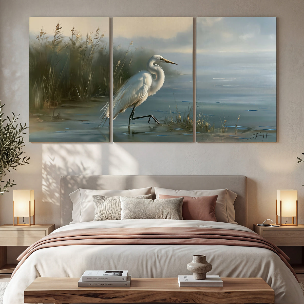 A white heron beside tall marsh grasses and still blue water 3 piece canvas wall art displayed in a bedroom