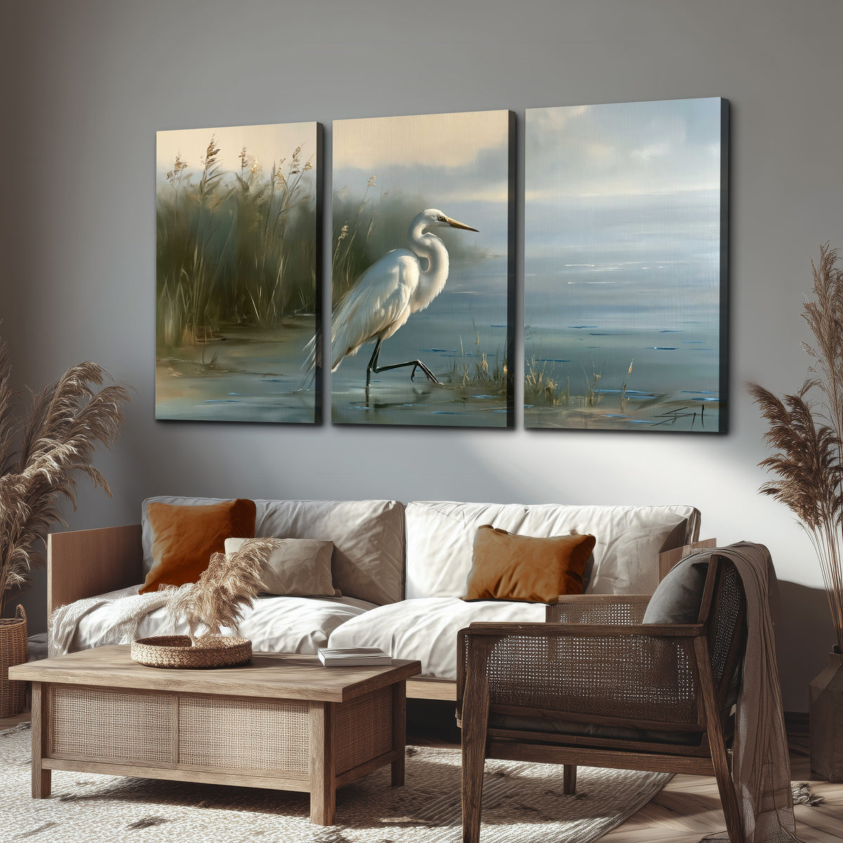 A white heron beside tall marsh grasses and still blue water 3 piece canvas wall art displayed in a rustic living room