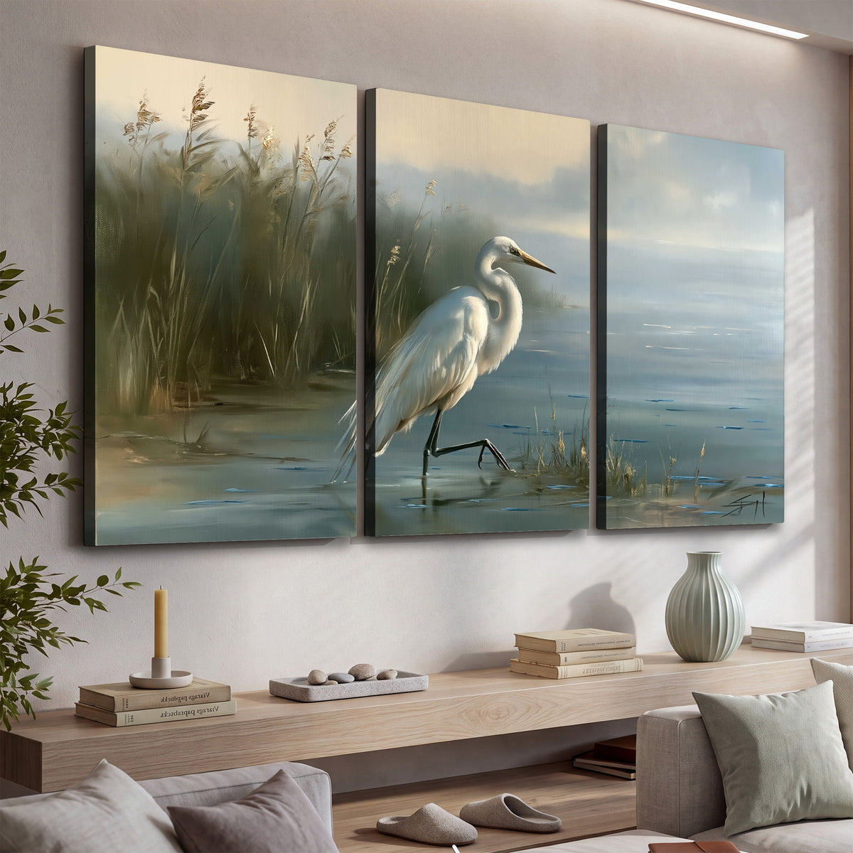 A white heron beside tall marsh grasses and still blue water 3 piece canvas wall art displayed in a console