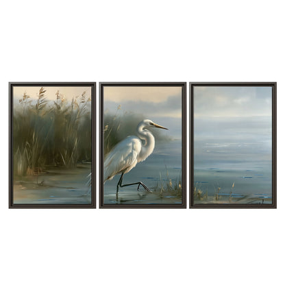 A white heron beside tall marsh grasses and still blue water 3 piece framed canvas wall art viewed straight on