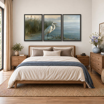 A white heron beside tall marsh grasses and still blue water 3 piece framed canvas wall art styled in an interior