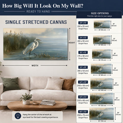 A white heron beside tall marsh grasses and still blue water single canvas wall art size guide above a sofa; room view is illustrative