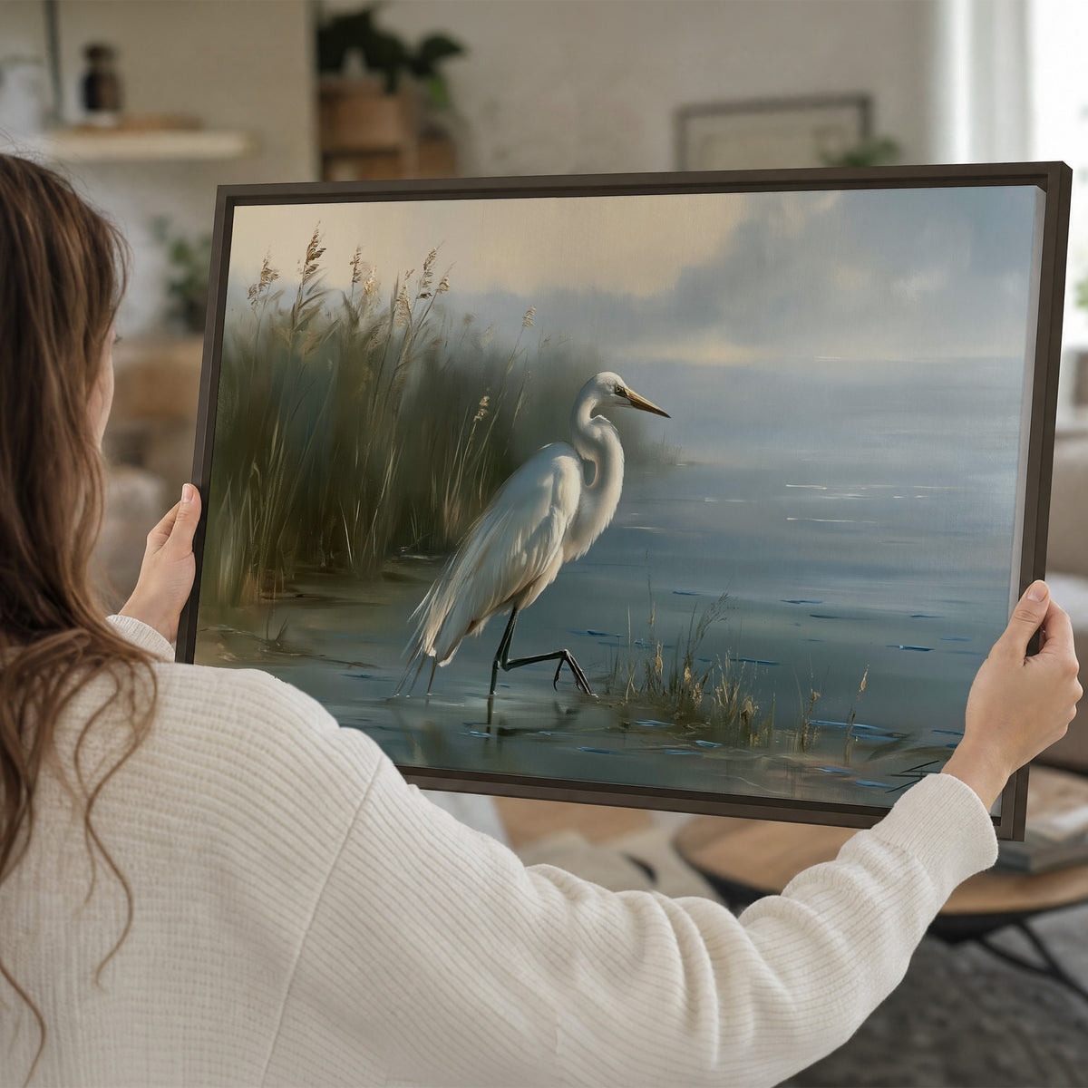 A white heron beside tall marsh grasses and still blue water single framed canvas wall art held in hands