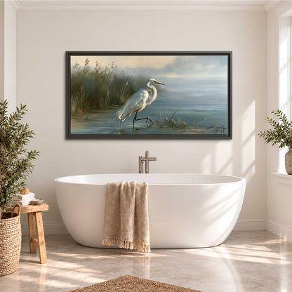 A white heron beside tall marsh grasses and still blue water single framed canvas wall art styled in an interior