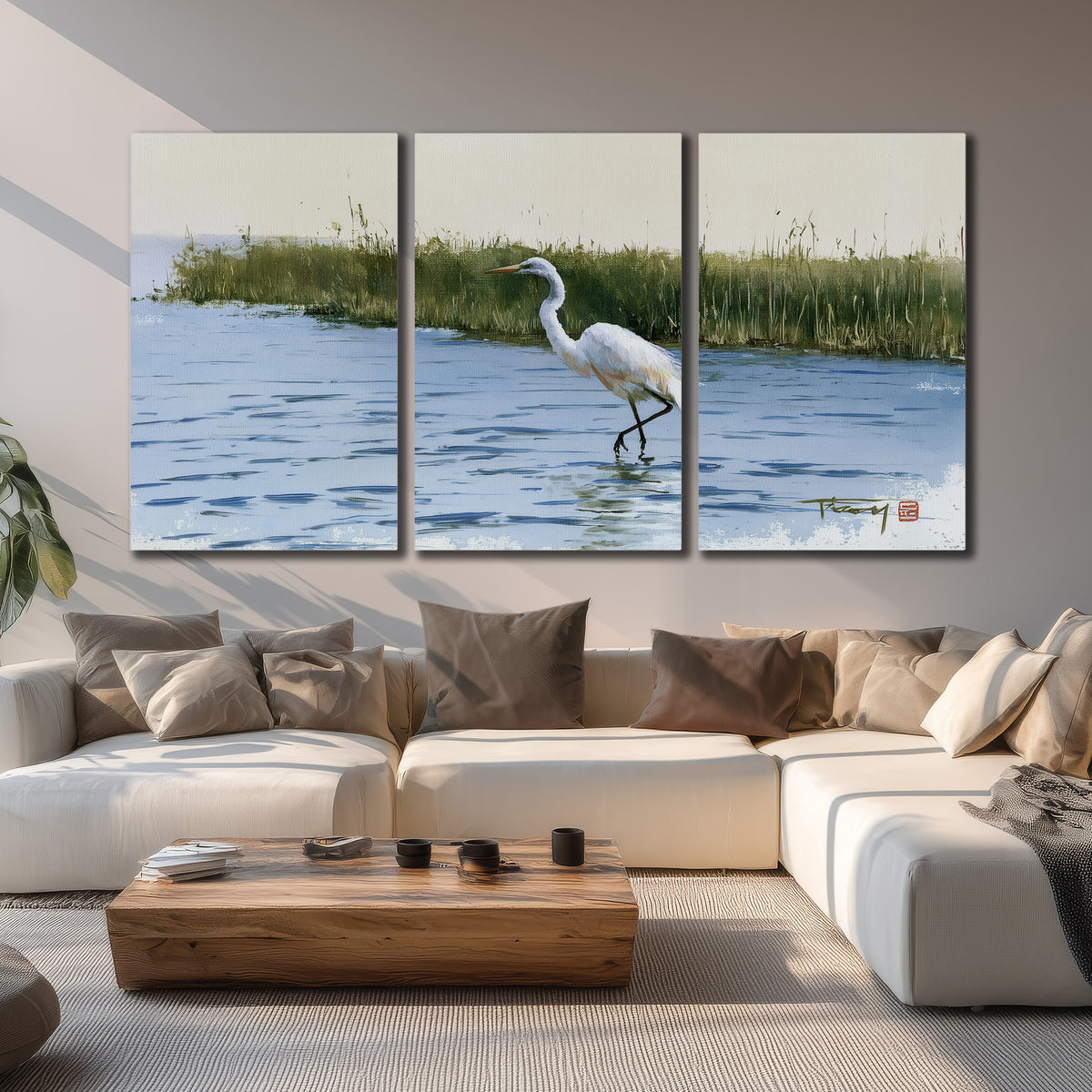 A white heron wading through bright blue water beside green reeds 3 piece canvas wall art displayed in a living room