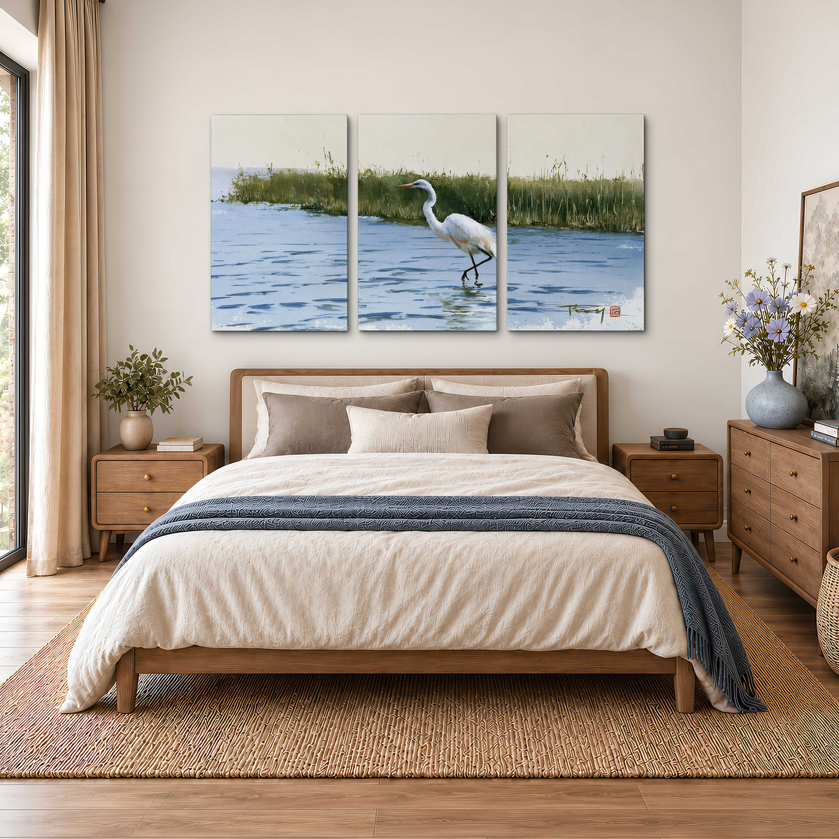 A white heron wading through bright blue water beside green reeds 3 piece canvas wall art styled in an interior