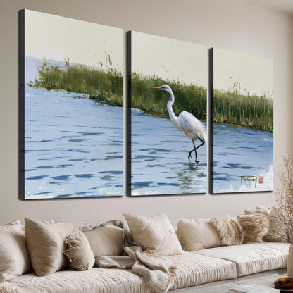 A white heron wading through bright blue water beside green reeds 3 piece canvas wall art room and product view