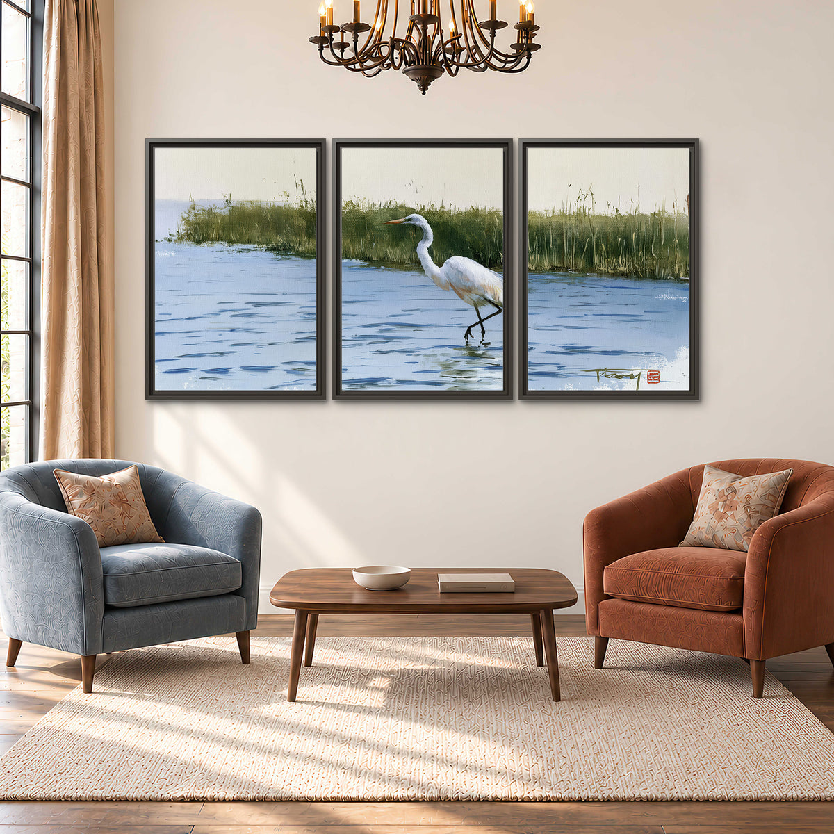 A white heron wading through bright blue water beside green reeds 3 piece framed canvas wall art styled in an interior