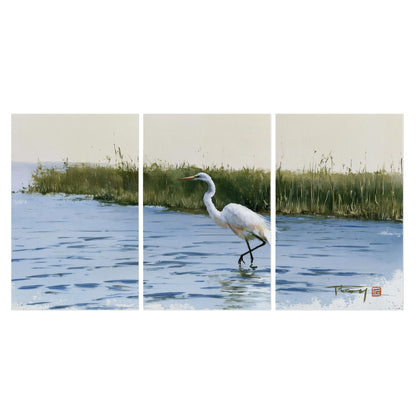 A white heron wading through bright blue water beside green reeds set of 3 poster prints viewed straight on
