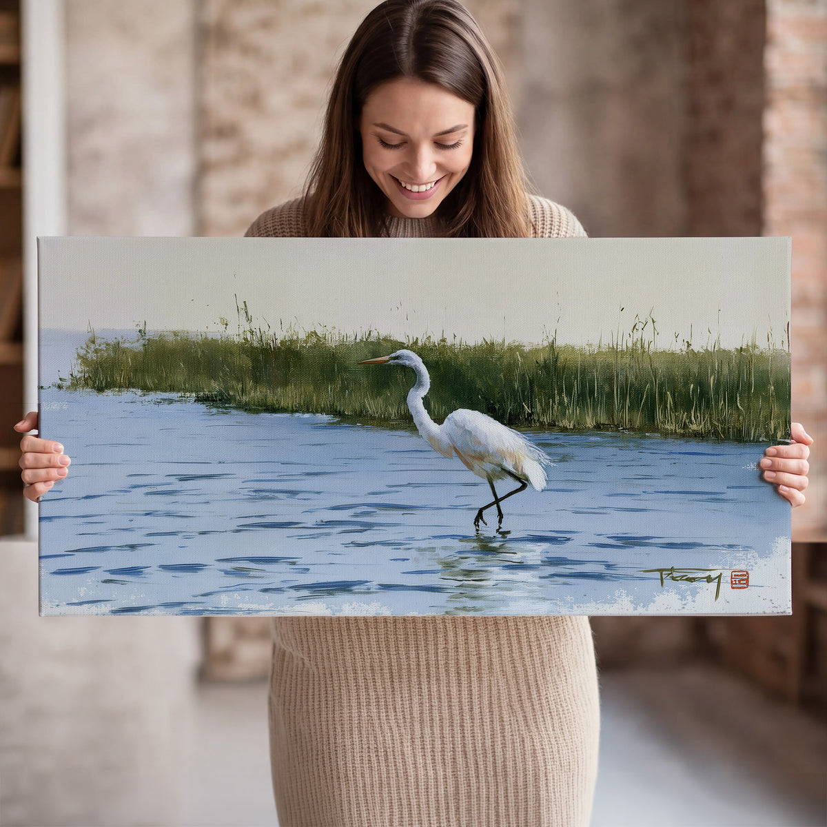 A white heron wading through bright blue water beside green reeds single canvas wall art held in hands