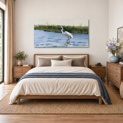 A white heron wading through bright blue water beside green reeds single canvas wall art styled in an interior