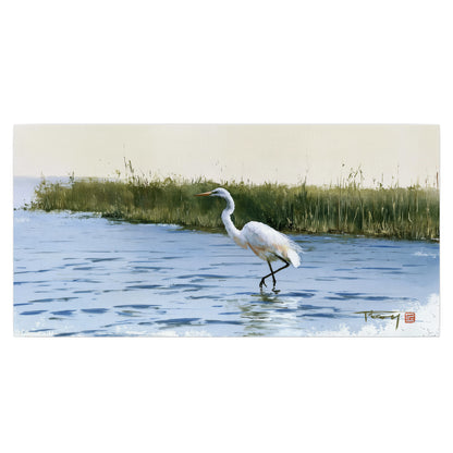 A white heron wading through bright blue water beside green reeds single poster print viewed straight on