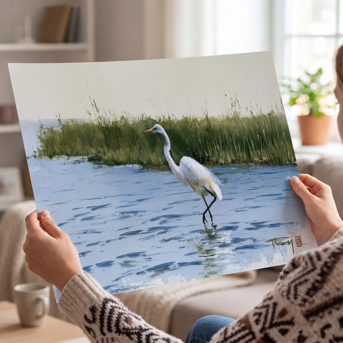 A white heron wading through bright blue water beside green reeds single poster print held in hands
