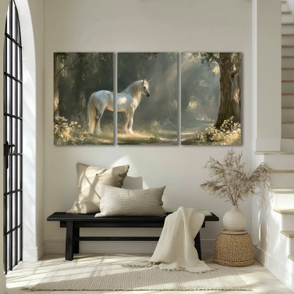 A white unicorn standing beneath arching trees in a softly lit woodland 3 piece canvas wall art displayed in a entryway