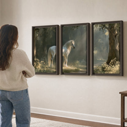 A white unicorn standing beneath arching trees in a softly lit woodland 3 piece framed canvas wall art three panel arrangement on a wall