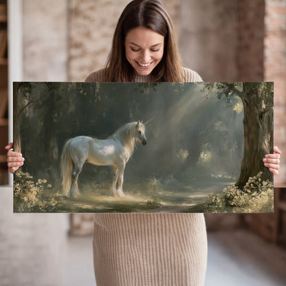 A white unicorn standing beneath arching trees in a softly lit woodland single canvas wall art held in hands