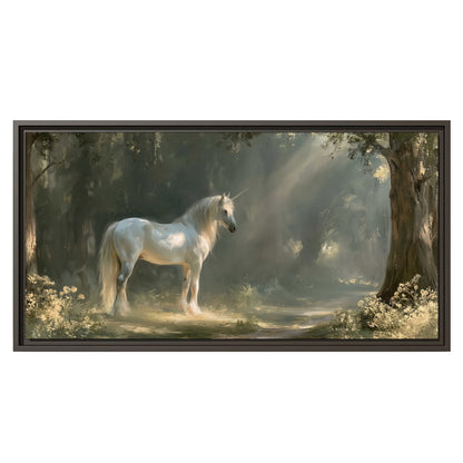 A white unicorn standing beneath arching trees in a softly lit woodland single framed canvas wall art viewed straight on