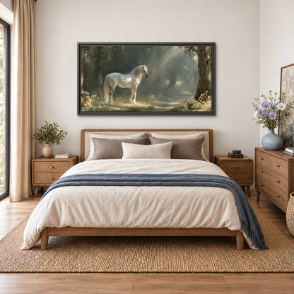 A white unicorn standing beneath arching trees in a softly lit woodland single framed canvas wall art styled in an interior