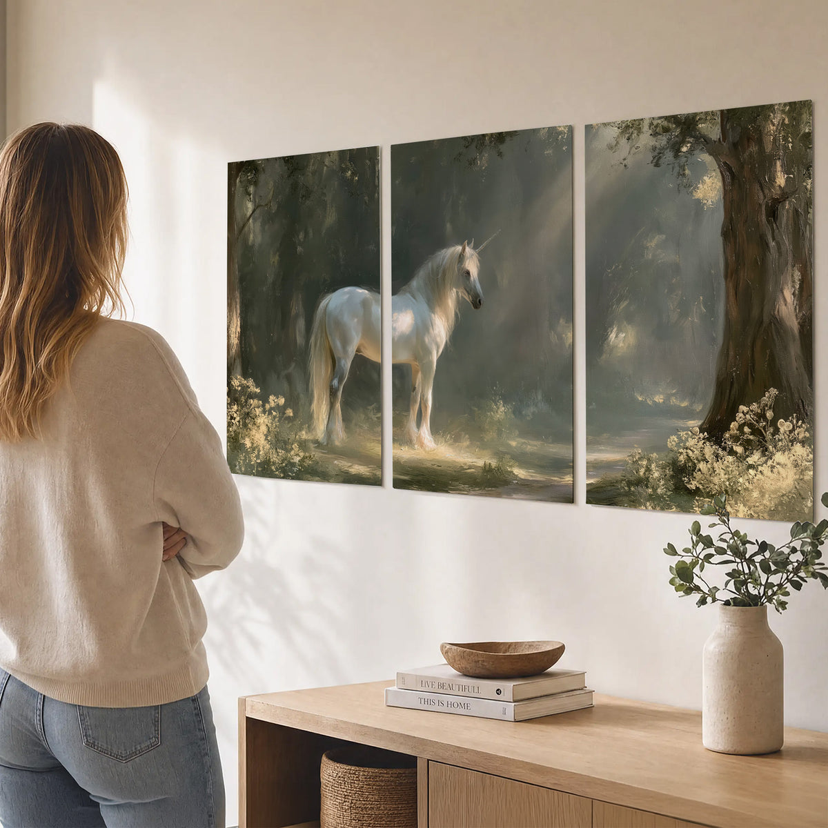 A white unicorn standing beneath arching trees in a softly lit woodland set of 3 poster prints three panel arrangement on a wall